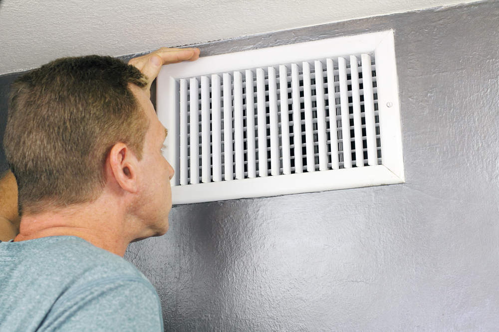 Mature,Man,Examining,An,Outflow,Air,Vent,Grid,And,Duct